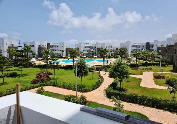 Un complexe hôtelier doté d’une piscine, de palmiers et d’un jardin bien entretenu.