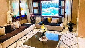 Una sala de estar con un sofá, una mesa de centro y un ventanal con vistas a un campo de golf.