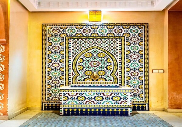 Una habitación con una amplia pared de azulejos ornamentales, con patrones geométricos y un diseño de arco central.