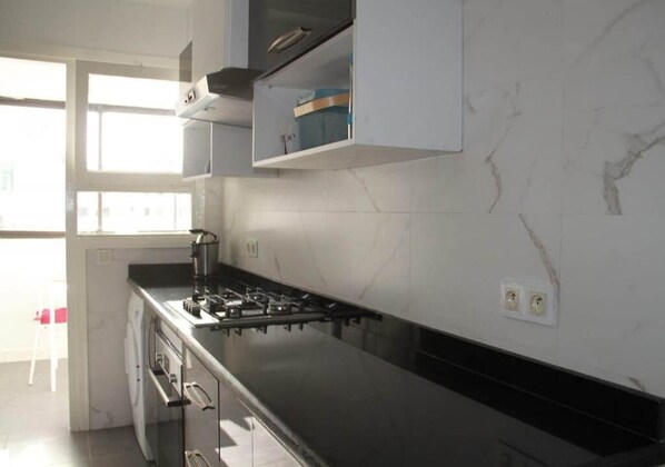 A modern kitchen with a black countertop, white marble backsplash, and built-in cabinets.