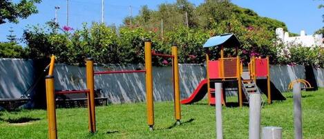 A playground with yellow and red equipment, a slide, and a climbing structure.