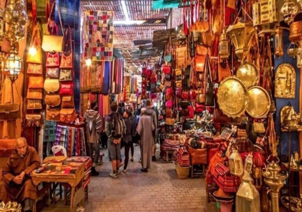Une rue étroite bordée d’étals où sont vendus des sacs, des textiles et d’autres articles.