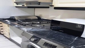 Een keuken met een gasfornuis, een magnetron en een wasmachine.