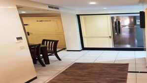 Een moderne keuken met een roestvrijstalen koelkast, een eethoek met een tafel en stoelen, en een deur naar een andere kamer.