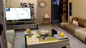 Ein modernes Wohnzimmer mit Flachbildfernseher, einem dekorativen Couchtisch, einer Couch und einer Wand mit kreisförmigen Ausschnitten.
