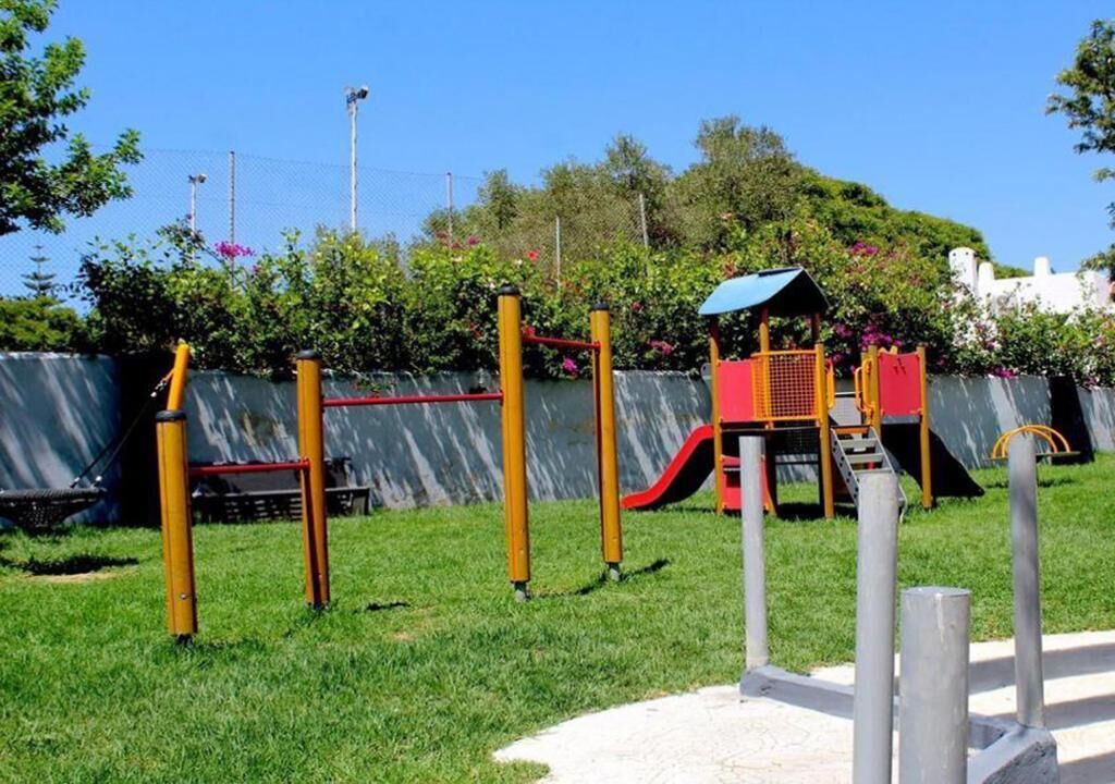 A playground with yellow and red equipment, a slide, and a climbing structure.