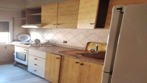 Een keuken met houten kastjes, een witte koelkast en een betegelde achterwand.