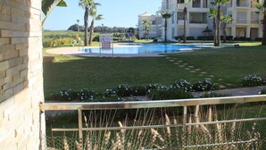 Un hotel con piscina, palmeras y un césped bien cuidado.