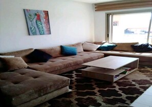 A living room with a sofa, a coffee table, and a patterned rug.
