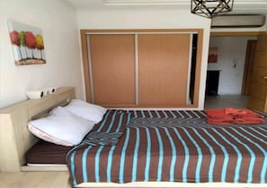 A bedroom with a bed, a wooden headboard, a wardrobe, and a painting on the wall.