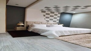 Een moderne slaapkamer met een groot bed, een nachtkastje, een lamp en een decoratief plafondpatroon.