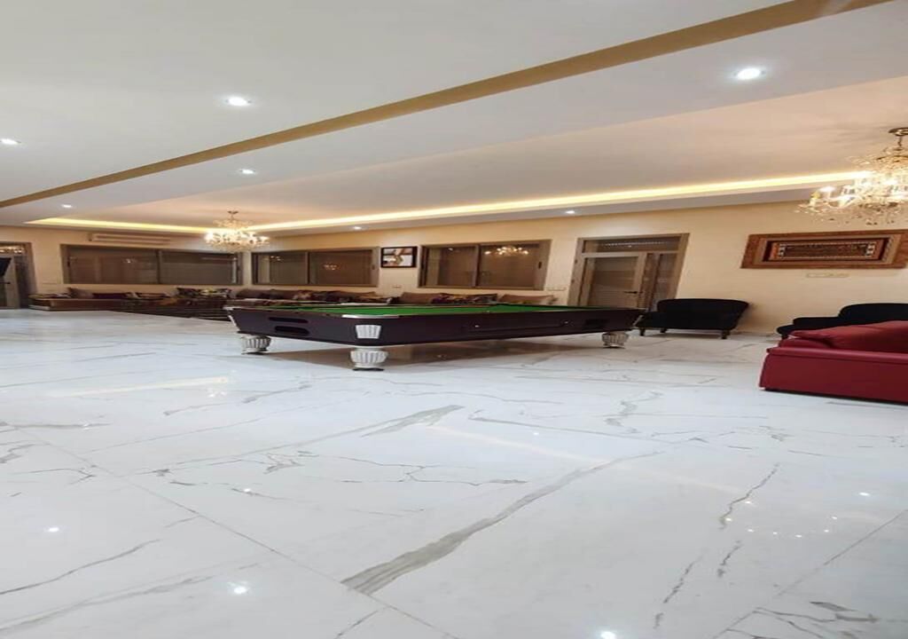 A spacious room with a pool table, comfortable seating, and a chandelier.