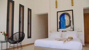 A bedroom with a bed, a chair, a small table, and a painting on the wall. - Pleasant villa with swimming pool in Marrakech 5100 (Marrakech)