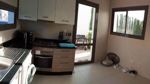 A kitchen with a washing machine, a microwave, and a stove. There is a window with a view of trees. - Superb villa with swimming pool in Taghazout Bay 5101 (Taghazout)