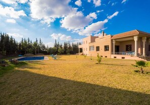 Une maison moderne dotée d’une piscine, d’un patio couvert et d’une pelouse bien entretenue.