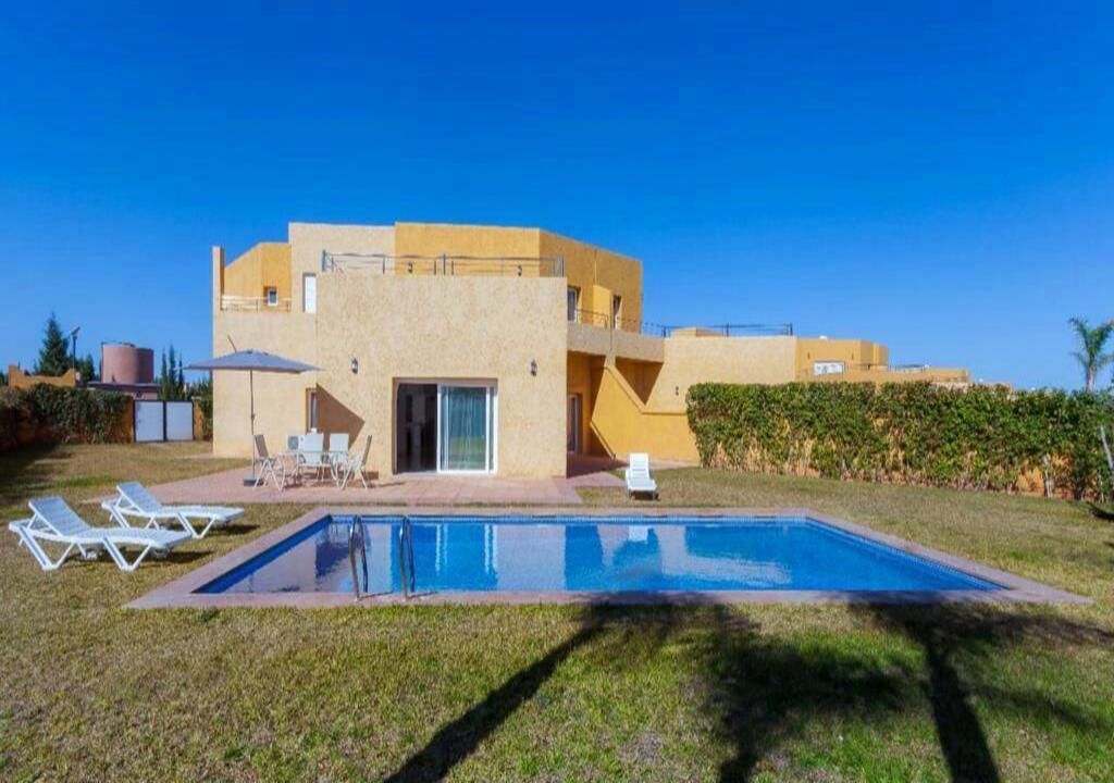 A modern two-story house with a swimming pool, outdoor seating, and a well-maintained lawn.