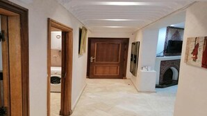 Un couloir avec une porte en bois, un mur blanc et un sol carrelé.