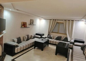 A modern living room with a sofa set, two coffee tables, and a flat-screen TV.