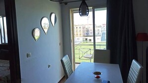 Un comedor con una mesa, sillas y vistas a edificios a través de una ventana.