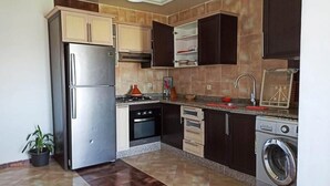 Una cocina equipada con refrigerador, estufa, horno, microondas, pileta y lavadora.