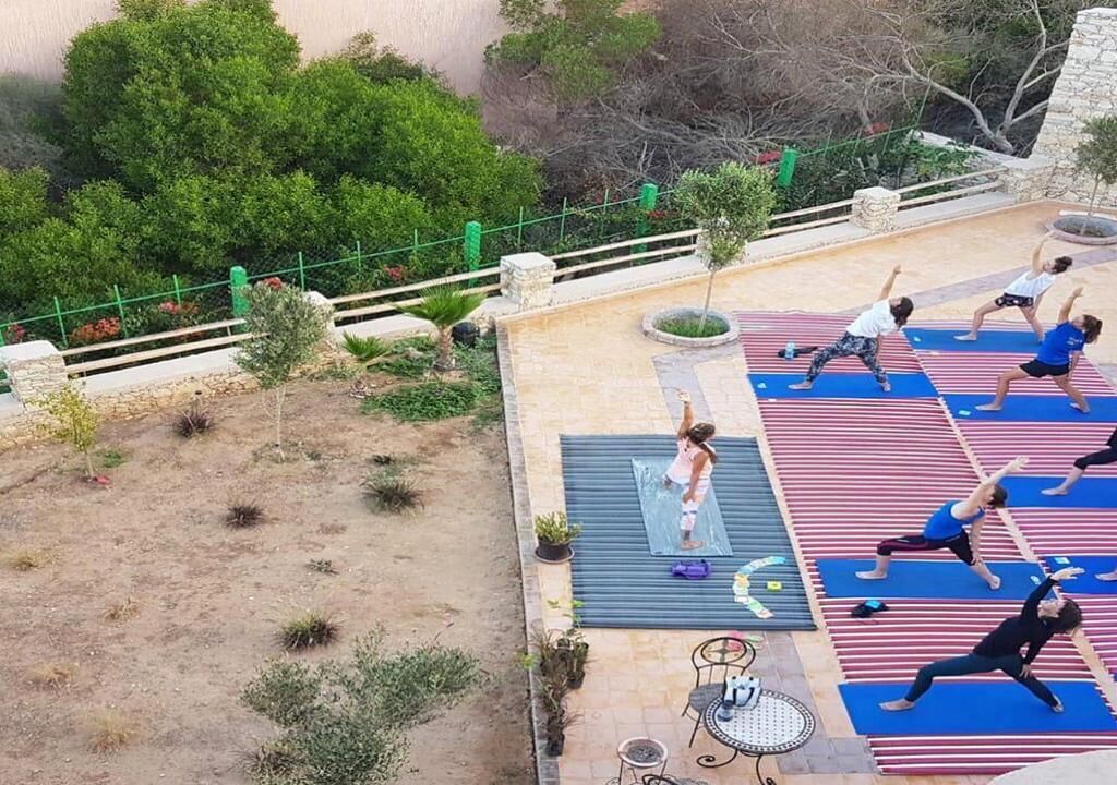 Un espacio para yoga al aire libre con colchonetas y árboles.