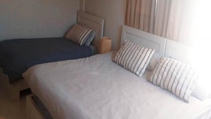Ein Doppelbett mit gestreiften Kissen und einem schlichten Kopfteil.