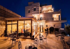 A modern building with a glass facade, outdoor seating area, and a stone wall. - Moroccan Surf Adventures 5187 (Imi Ouaddar)