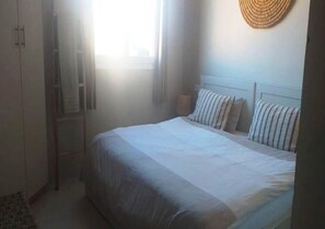 A bedroom with a bed, a wardrobe, and a window with curtains. - Moroccan Surf Adventures 5188 (Imi Ouaddar)