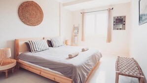Ein Schlafzimmer mit einem hölzernen Bett, einem gewobenen Kopfteil, einem Nachttisch und einem kleinen Hocker.