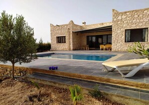 A modern stone house with a swimming pool, outdoor seating, and a small tree. - Pleasant villa with swimming pool 5195 (Essaouira)