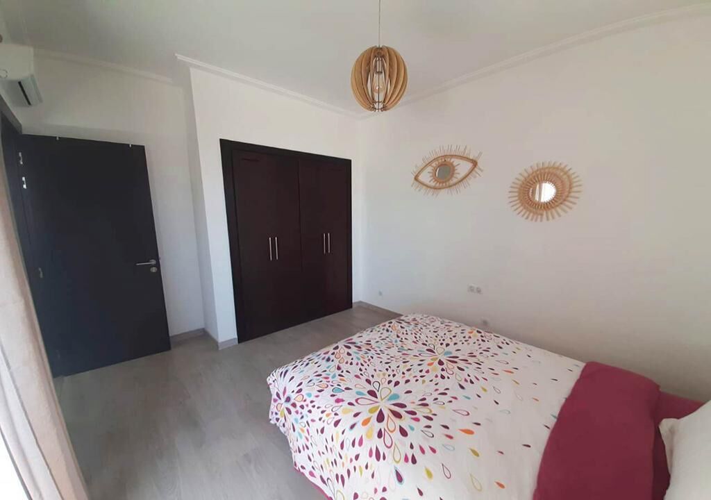 A bedroom with a bed, a wardrobe, and a ceiling light fixture.