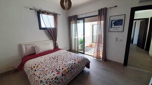 A bedroom with a bed, a window with curtains, a door, and a hallway. - Superb villa in Taghazout bay 5197 (Taghazout)