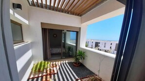 A balcony with a striped floor, potted plants, and a view of buildings. - Superb villa in Taghazout bay 5197 (Taghazout)
