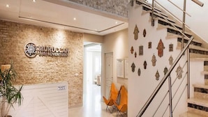 A reception area with a Moroccan Surf Adventures sign, a reception desk, a staircase, and a wall with decorative items. - Moroccan Surf Adventures 5223 (Imi Ouaddar)