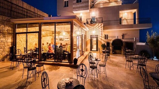 A modern building with a glass facade, outdoor seating area, and a stone wall. - Moroccan Surf Adventures 5223 (Imi Ouaddar)
