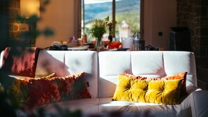 A white sofa with yellow and red cushions in a room with a stone wall and a large window overlooking a landscape. - Private Villa with private pool, A/C, WIFI, sauna, hot tub, TV, patio, close to Greve In Chianti (Radda In Chianti)