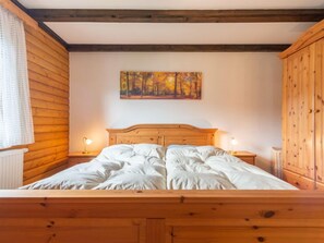 A wooden bed with a headboard, two bedside tables with lamps, a painting on the wall, and a wooden wardrobe. - Am Hohen Bogen by Interhome (Arrach)
