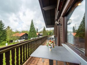 A balcony with a table and a vase of flowers, overlooking a residential area with houses and trees. - Am Hohen Bogen by Interhome (Arrach)