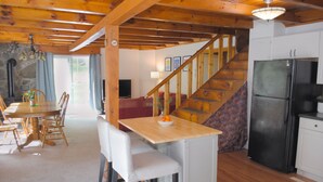 A wooden interior with a dining area, kitchen, and staircase. - Cozy 4bd - Ski Okemo, Killington, Magic & Bromley (Chester)