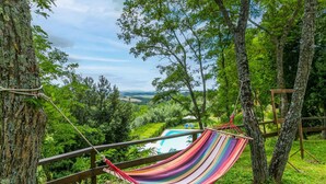 A hammock between trees overlooking a pool and lush greenery. - Beautiful apartment in villa for 6 people with pool, TV and patio (Poggibonsi)