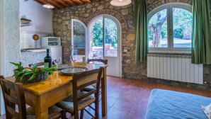 A rustic kitchen with stone walls, wooden ceiling beams, and a dining area with a table set for two. - Nice apartment in villa for 4 people with pool, TV and patio (Poggibonsi)