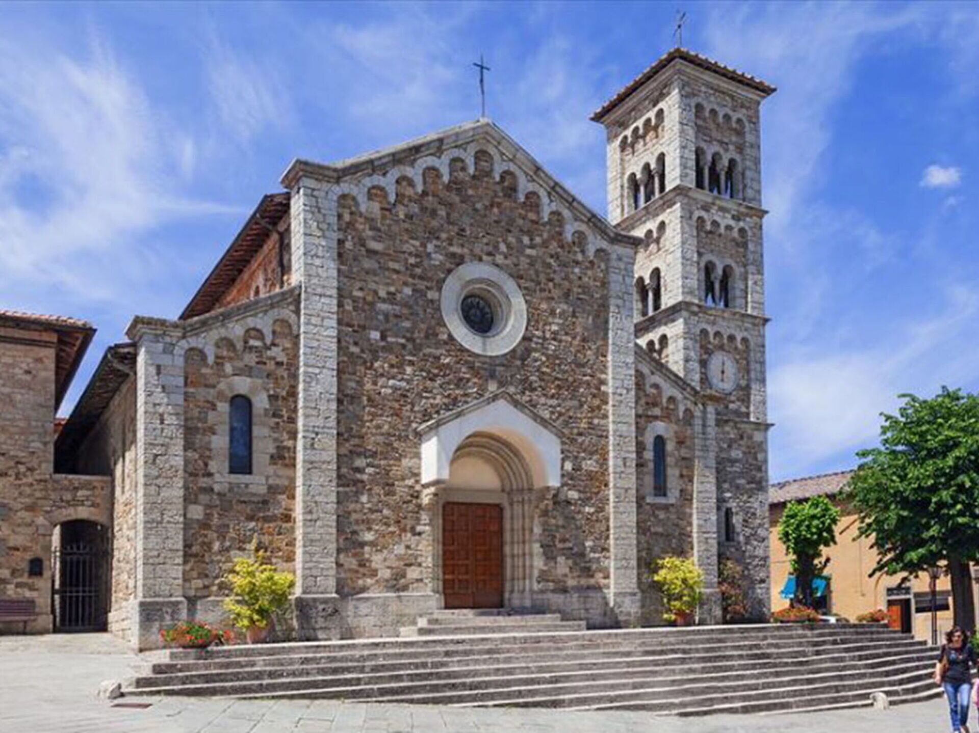 A historic stone church with a bell tower, arched windows, and a circular window above the entrance.
