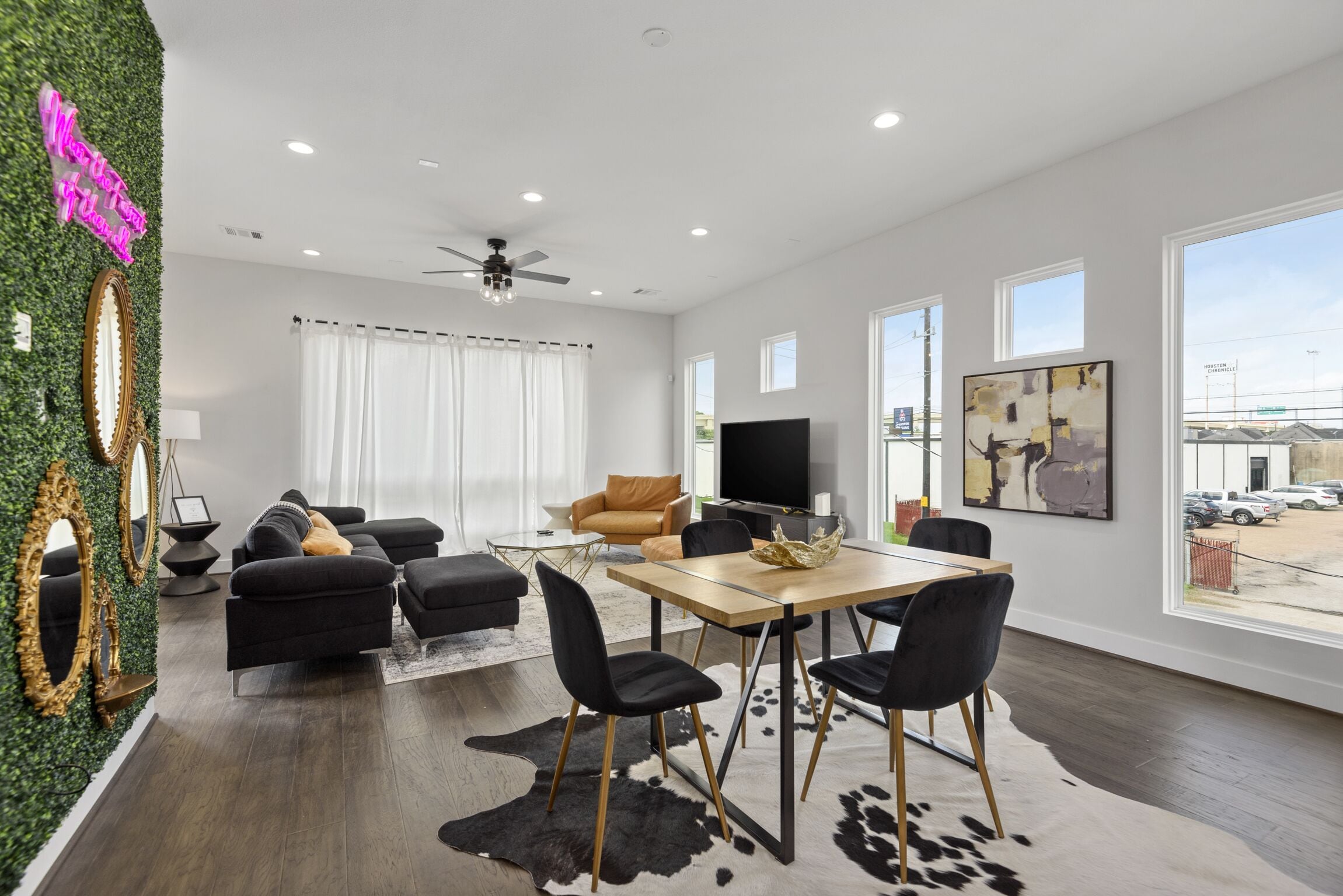 A modern living room with a sofa, chairs, a dining table, and a TV.