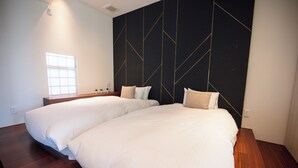 A double bed with white linens in a room with a dark geometric wall design and wooden flooring. - Wellis Villa HANARE (Awaji)