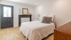 A bedroom with a bed, a dresser, a door, and a fireplace. - Bloomingdale Beauty - Sleeps 4 in Style! (Washington)