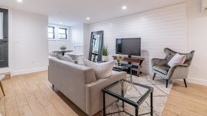 A modern living room with a sofa, armchair, TV, and a small table. - Bloomingdale Beauty - Sleeps 4 in Style! (Washington)
