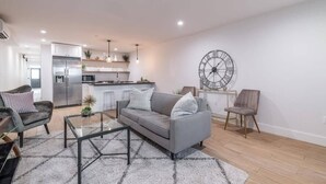 A modern living room with a grey sofa, a glass coffee table, and a large wall clock. - Bloomingdale Beauty - Sleeps 4 in Style! (Washington)