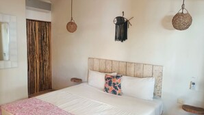 A bedroom with a large bed, a wooden headboard, a bedside table, and a hanging macrame light fixture. - Master Room on 5th, one block to the beach (Playa del Carmen)