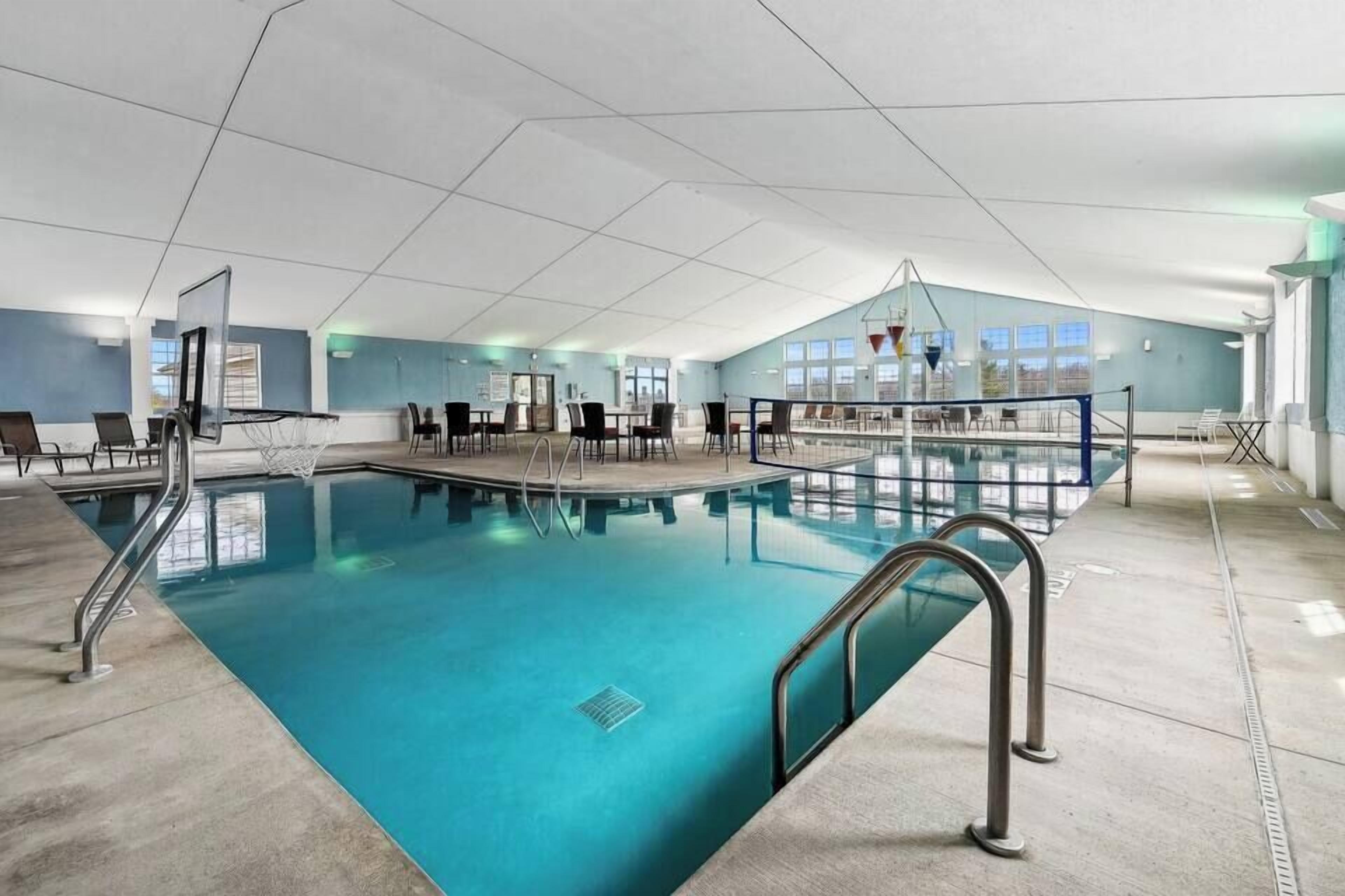 Una piscina interior con aro de baloncesto, zona de estar y un ventanal grande.