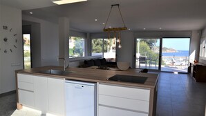 A modern kitchen with a dishwasher, a large island, and a view of the sea. - Villa Magnifica, L'Estartit - Center (Estartit (L´))